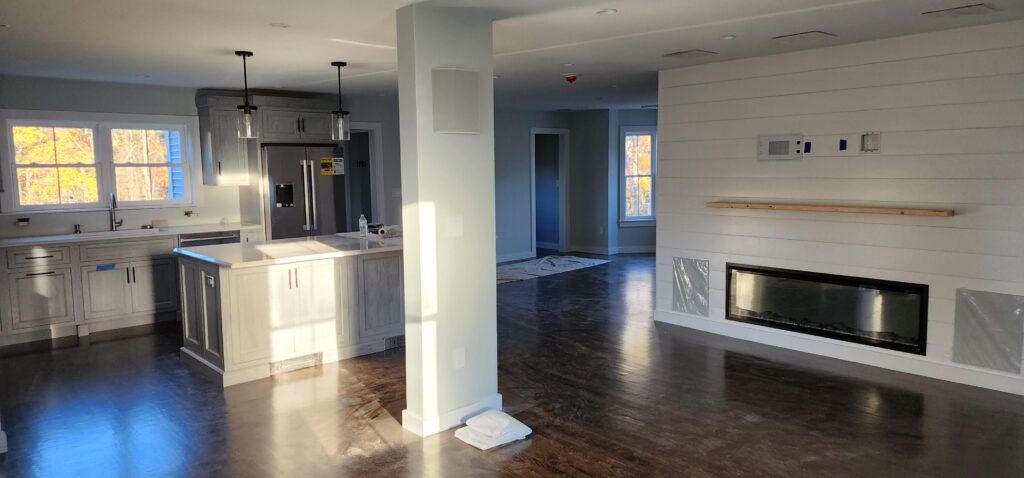 Open kitchen and living room with a shiplap fireplace wall and a linear fireplace