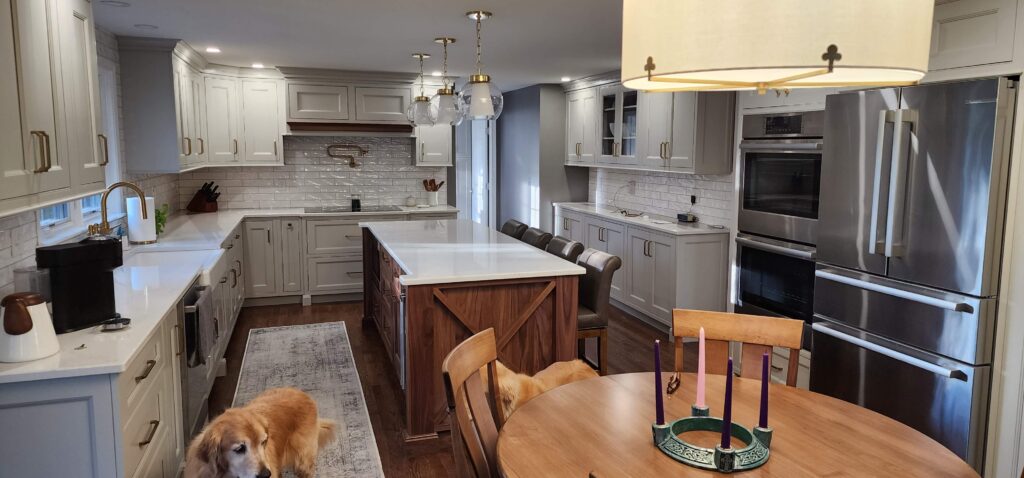 Gray painted kitchen with a dark wood island, white counters and a dining table