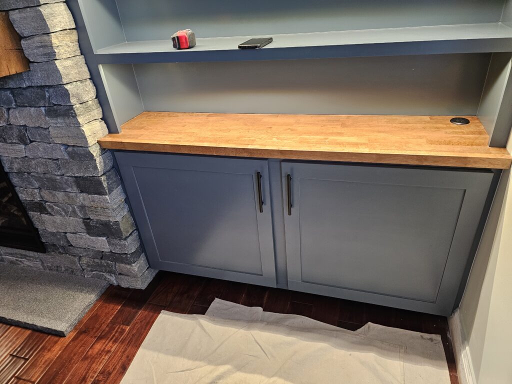 Built-in blue cabinet with a butcher-block top beside a stone fireplace