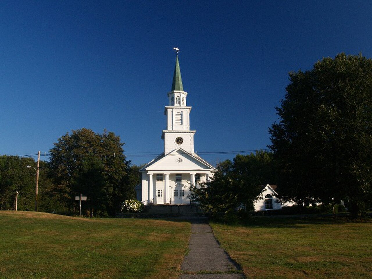 White church with a tall steeple on the town common in Boylston center