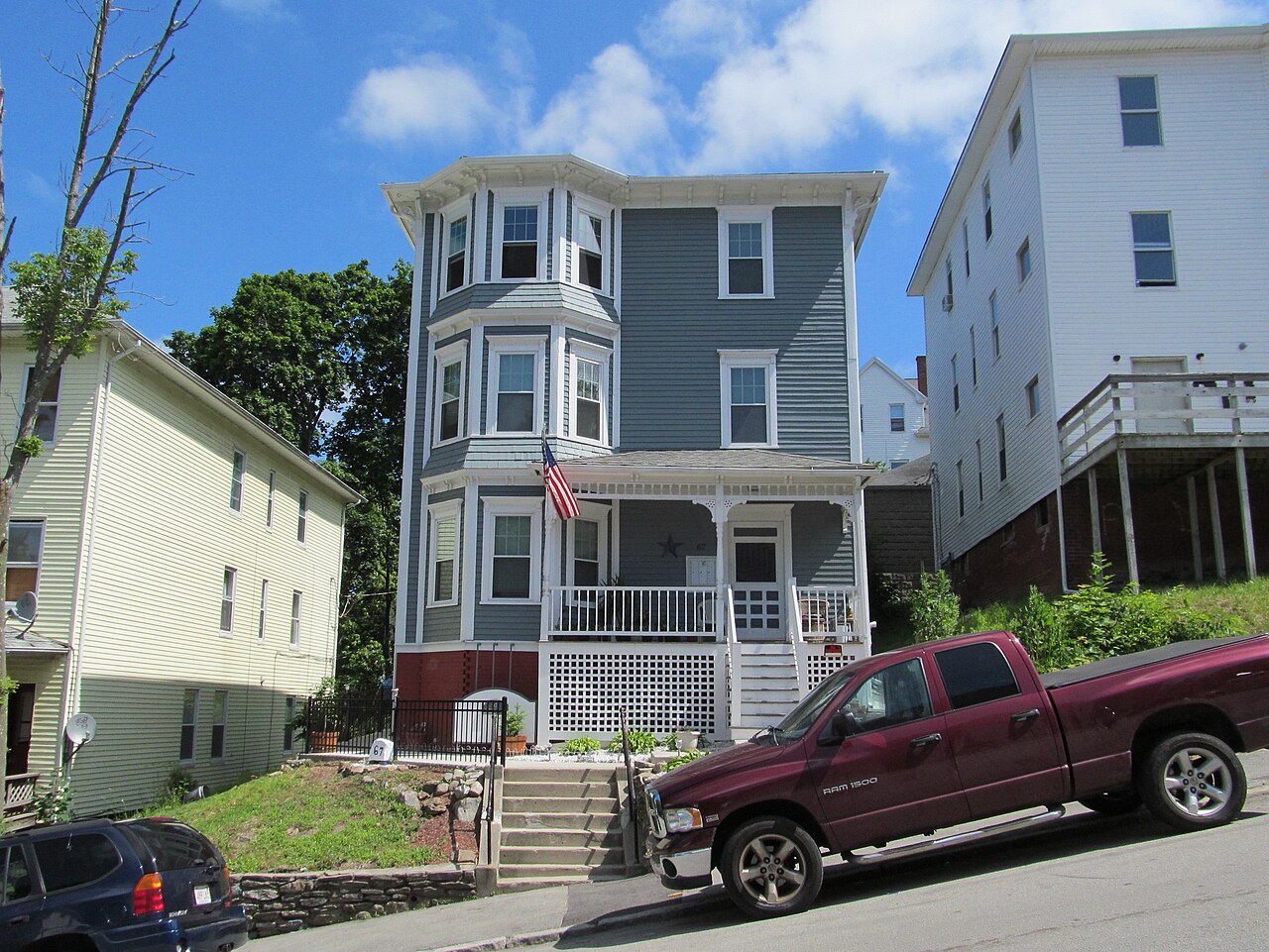 A three-story wood-frame three-decker house with stacked front porches on a Worcester street
