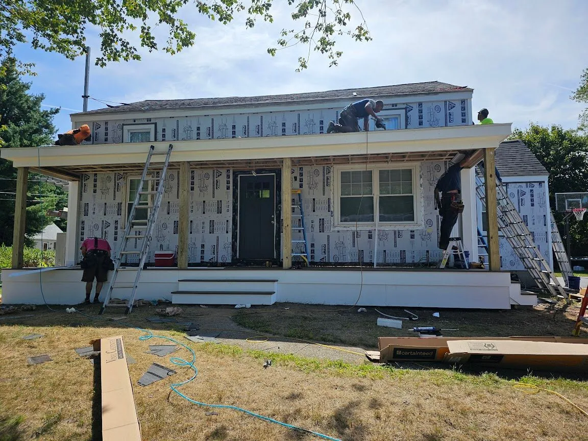 Crew building a covered front porch across the front of a house wrapped in house wrap