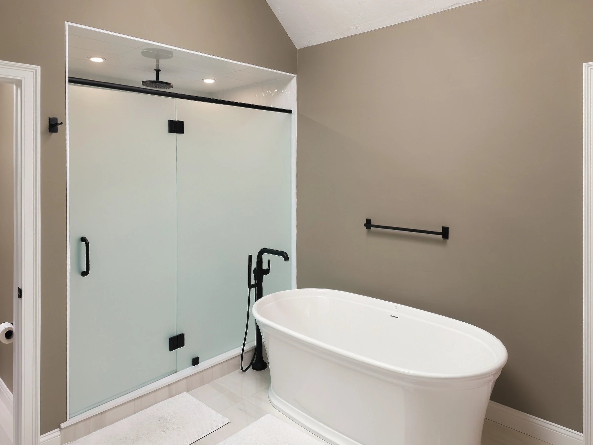 White freestanding tub beside a glass shower enclosure with dark fixtures.