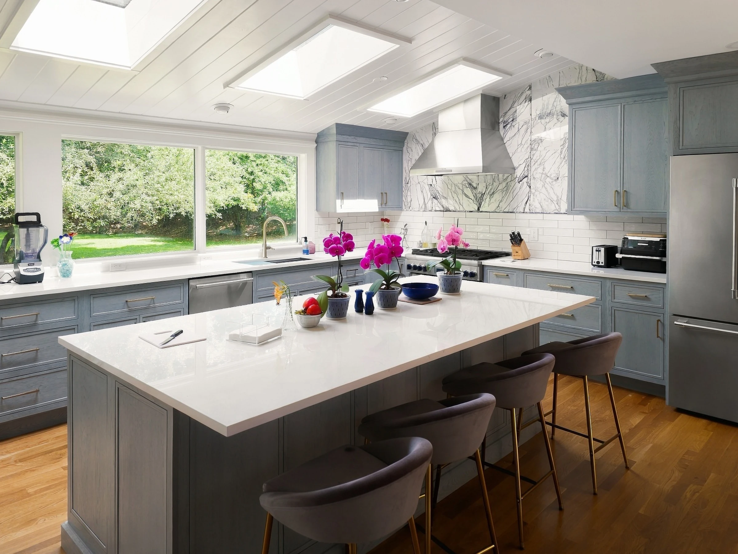 Gray kitchen cabinets and a large island beneath skylights.