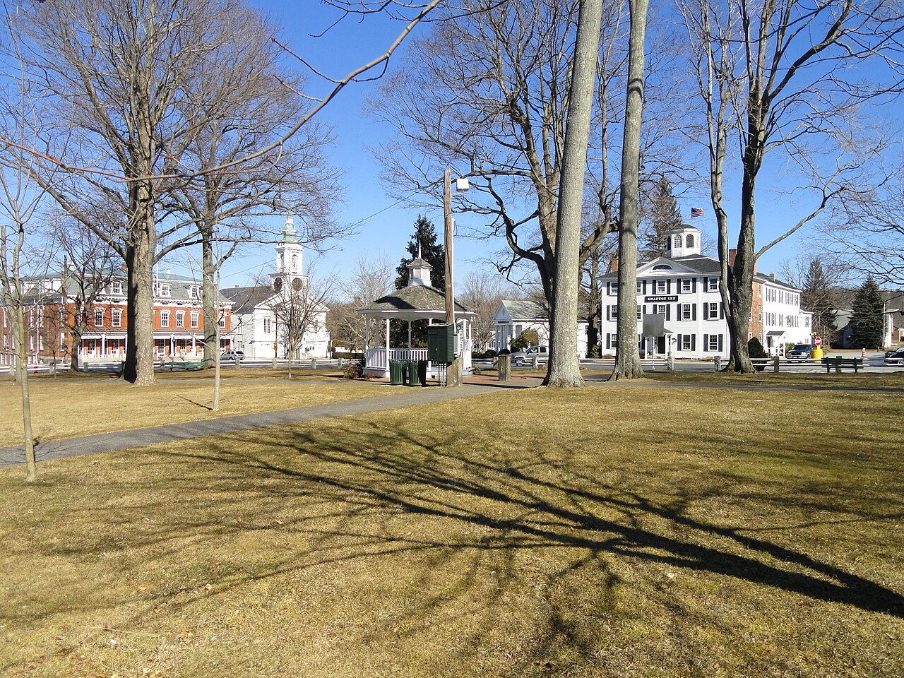 Grafton Common in early spring, with bare trees, a small gazebo and white and brick buildings around the green