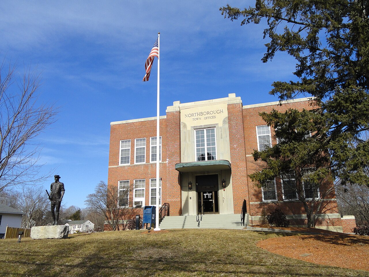 Northborough Town Offices, a two-story brick building with a flagpole and a bronze statue on the front lawn