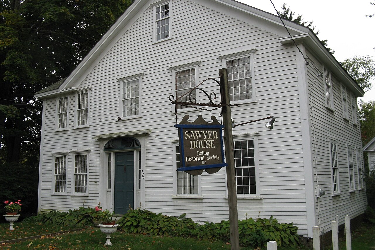 The Sawyer House, a white clapboard colonial with a hanging Bolton Historical Society sign out front