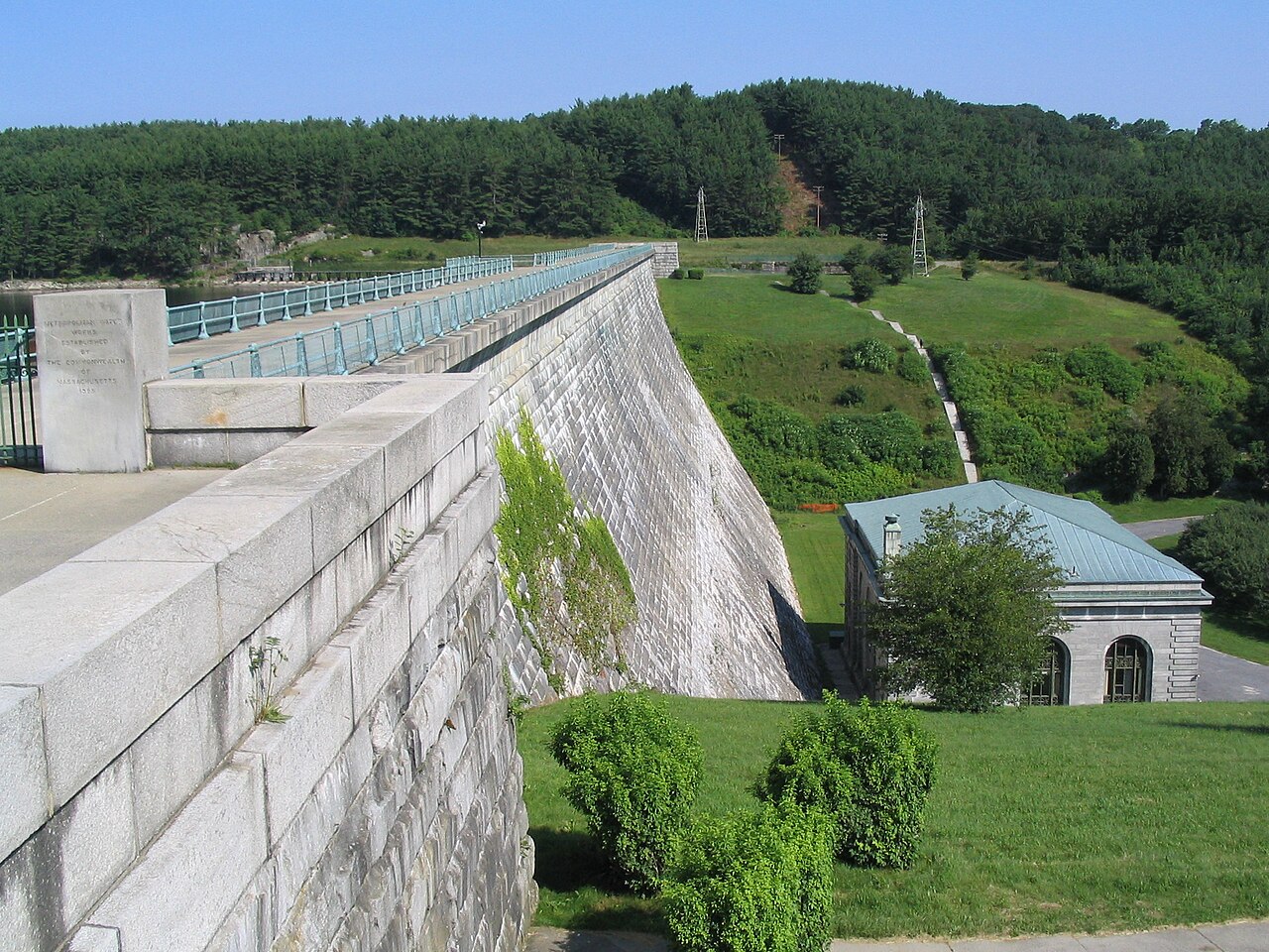 The granite Wachusett Dam with water spilling over its face into the Nashua River below